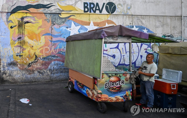 지난해 12월 29일(현지시간) 차베스 벽화 앞에서 햄버거 파는 상인